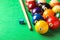 Many colorful billiard balls, cue and chalk on green table. Space for text