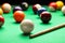 Many colorful billiard balls and cue on green table