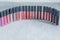 Many colorful, bright professional lipstick lined up in rows, on white gray background, close-up, makeup artist, makeup