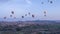 Many colorful hot air balloons flight above mountains - panorama of Cappadocia at sunrise.