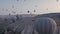 Many colorful hot air balloons flight above mountains - panorama of Cappadocia at sunrise.