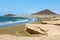 Many colorful kites on beach and kite surfers riding waves and flying during windy day in canarian El Medano in Tenerife with