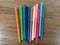 Many colorful pens placed on a wooden background