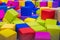 Many colorful soft blocks in a kids` pool at a playground. Bright multi-colored soft cubes, geometric toys. Multicolored backgrou
