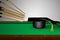 Many cue sticks aiming to hitting a graduation hat on a pool table. Cooperation or teamwork or partnership or Congratulate the