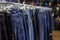 Many different blue Jeans on a hanging rack in the clothes shop store