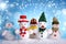 Many different decorative snowmen on blue background with snowflakes, bokeh effect