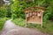 Many different forms of bird feeders. Birdhouses hang on a wooden information stand.