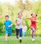 Many different kids, boys and girls running in the park on sunny summer day in casual clothes.