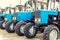 Many different tractors standing in row at agricultural fair for sale outdoors.Equipment for agriculture.Heavy industrial machines