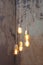 Many different vintage light bulbs hanging from ceiling. Loft pendant lamps on background of rough cement plaster on wall. Minimal