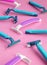 Many disposable purple and blue razors on a pink background