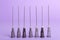 Many disposable syringe needles on violet background