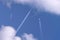 Many distant passenger jet planes flying on high altitude on clear blue sky leaving white smoke trace of contrail behind