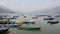 Many empty wooden colored boats on a smooth lake during the day against the backdrop of a mountain valley