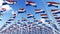 Many flags of Netherlands on flagpoles against blue sky.
