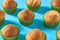 Many fluffy muffins in green paper molds scattered on blue