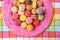 Many french macarons selection of colorful pastries on pink dessert plate top view. Retro vintage home kitchen