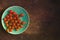 Many fresh cherry tomatoes in blue plate on brown background. Free space for your text.