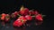 Many fresh raw strawberries falling at black background. Healthy superfood