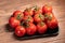 Many fresh red tomatoes with their green stems on brown wooden table close-up