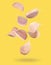 Many garlic cloves falling on yellow background