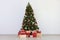 Many gifts under a festively decorated Christmas tree in a bright interior