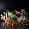 Many glasses and glasses with multicolored appetizing fruit cocktails and juices on black,