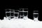 Many glasses of vodka standing on ice on black background