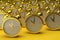 Many golden alarm clocks on a yellow background. Time management, deadline concept. 3D render
