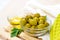 Many green whole olives and olive oil in the glass bowls on light wooden board background in the kitchen.