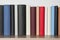 Many hardcover books on wooden table near white wall