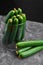 Many harvest cucumbers In vase on the grey concrete background. Top view