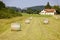 Many hay bales packed with italy flags logo on a large mowed meadow on day without people