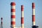 Many high red and white industrial pipes over clear cloudless blue sky on sunny day