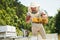 Many of hives. Beekeeper works with honeycomb full of bees outdoors at sunny day