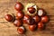 Many horse chestnuts on wooden table, flat lay