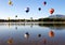 Many Hot air balloons flying over a Mountain Lake