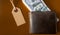Many hundreds of dollars banknotes in a leather wallet with a brown tag, price tag on a brown background. Flat lay. Background,