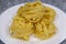Many Italian egg pasta nest on a white plate on a gray background