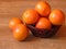 Many juicy orange shiny ripe grapefruit fruit in a basket on oak tree background. Retro rustic style. Wallpaper or background.