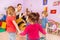 Many kids clap hands with teacher in kindergarten
