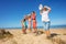 Many kids jump on the beach near sea lifting hands