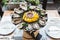 Many kinds of Fresh Oysters served in round tray with slice lemon and spicy sauce