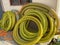 Many large coils of yellow thick plastic hoses of large diameter for pumping liquids in an industrial warehouse