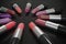 Many lipsticks in circle on black background. 3D rendered illustration