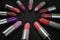 Many lipsticks in circle on black background. 3D rendered illustration