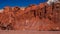 Many llamas walking under bright red mountain