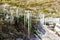 Many long white icicles hanging from a rocky overhang, red rocks