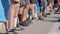 Many male prosthetic feet stand in row close to each other on asphalt road